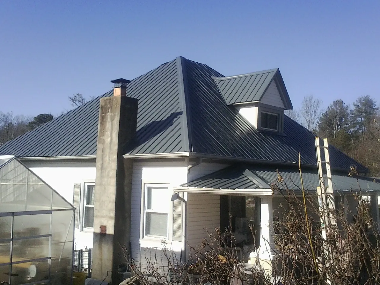 Dark blue standing seam metal roof on a white farmhouse with dormer — Slate & Tile Roof Repair by Roofing Brothers in Reesville