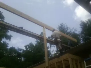 Carpenter setting a ridge beam over a new addition frame — Ice Dam Removal by Roofing Brothers in Reesville