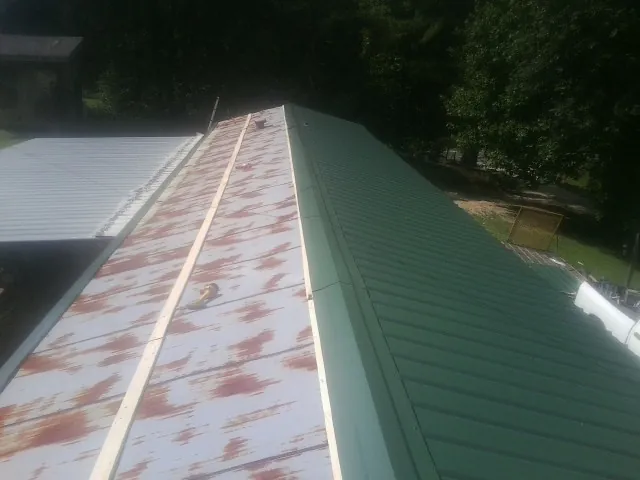 Old rusted panels beside newly installed green metal roofing — Wind Damage Roof Repair by Roofing Brothers in Reesville