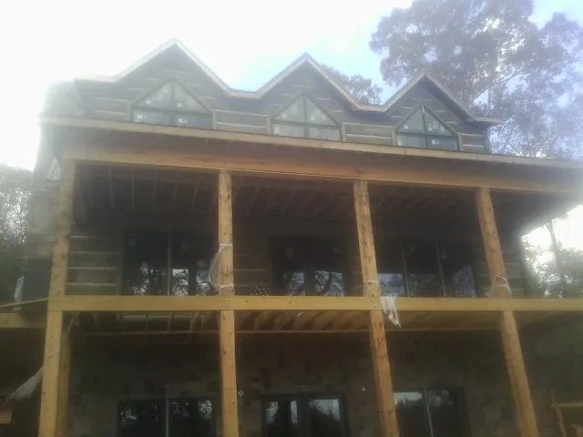 Dormers and porch framing on a large log home under construction — Roof Coating work by our crew in Reesville