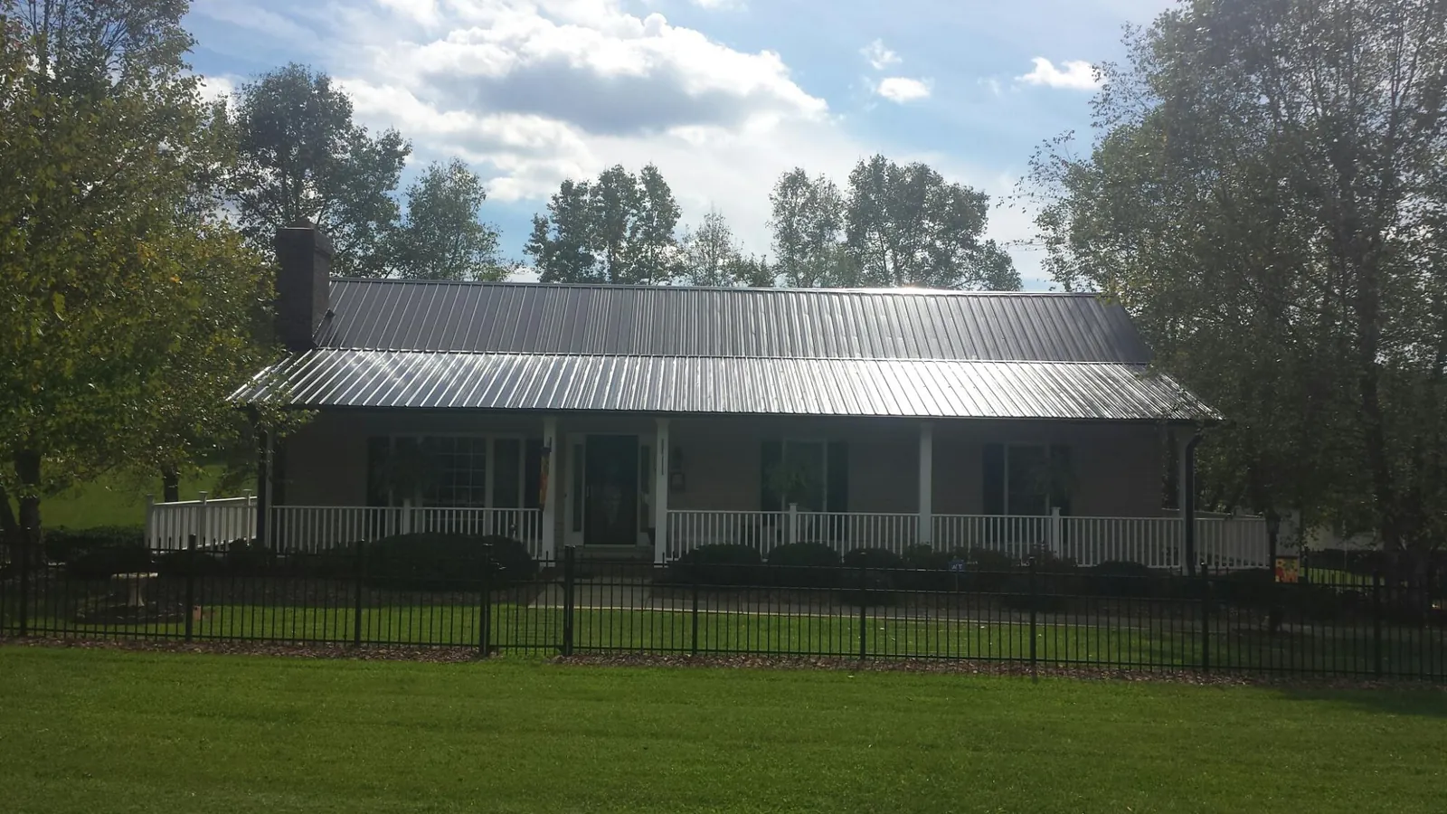 Gray metal roof on a brick ranch with a full width front porch — Gutter Guard Installation work by our crew in Reesville