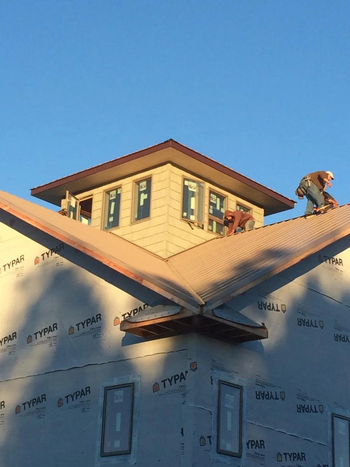 Roofers working around a rooftop cupola on a new metal roof at sunset — Roof Waterproofing in Reesville by Roofing Brothers
